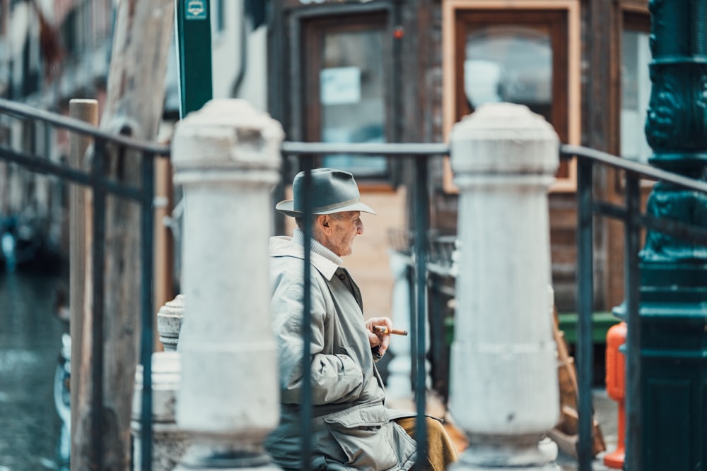 man wearing gray coat near black metal railings