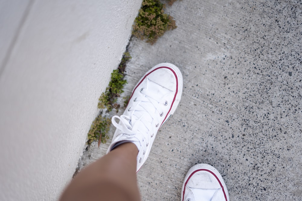 person wearing pair of white low-top lace-up shoes