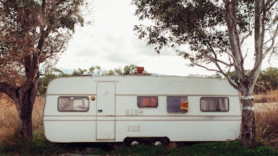 white camper trailer in between green trees