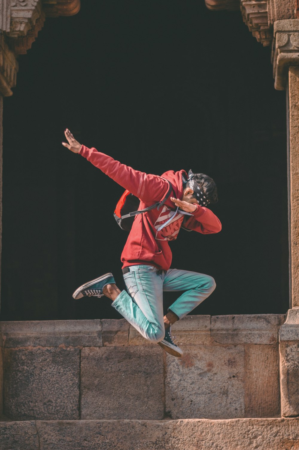 man jumping while raising hands in slant position