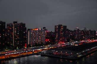 A vibrant cityscape at dusk highlighting modern apartment buildings with warm lights glowing from windows.