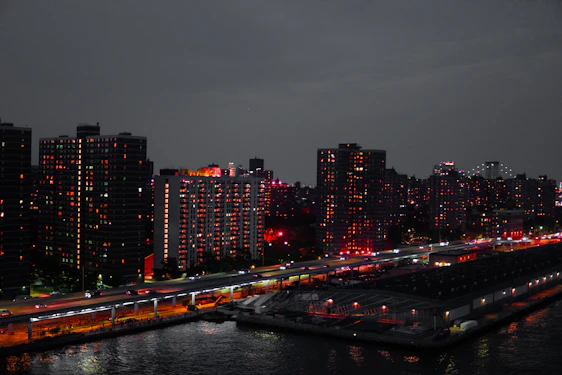 A sleek, modern cityscape at dusk showcasing upscale residential buildings with warm lights glowing from windows.