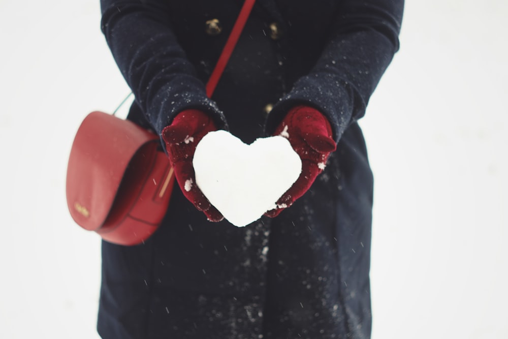pessoa segurando neve em forma de coração