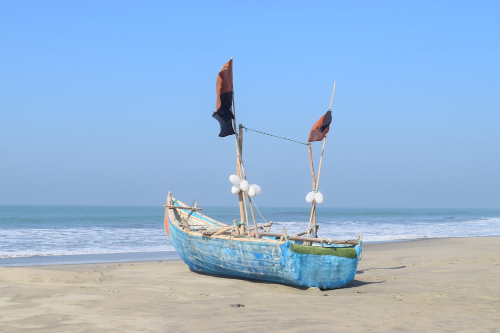 barco azul na costa da praia sob o céu ensolarado azul durante o dia