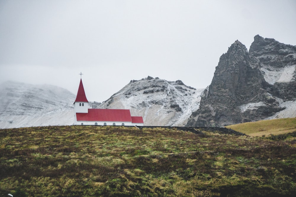 white and red concrete house near mountain during daytime