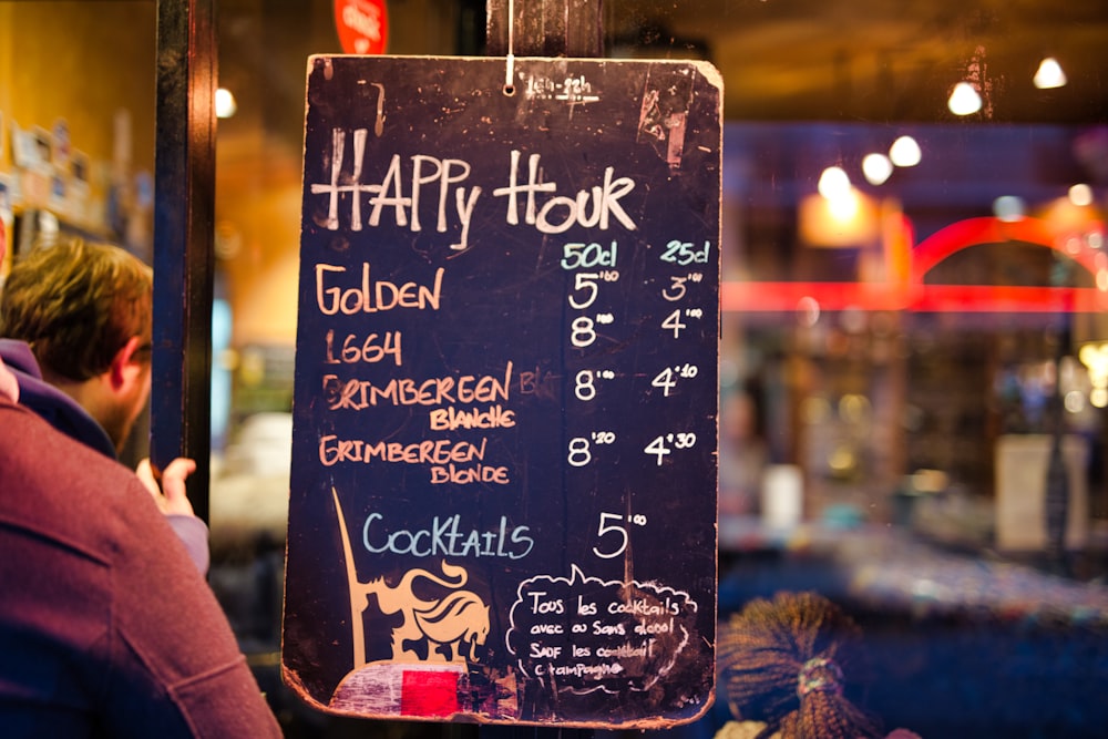 black Happy Hour signage near man in brown jacket