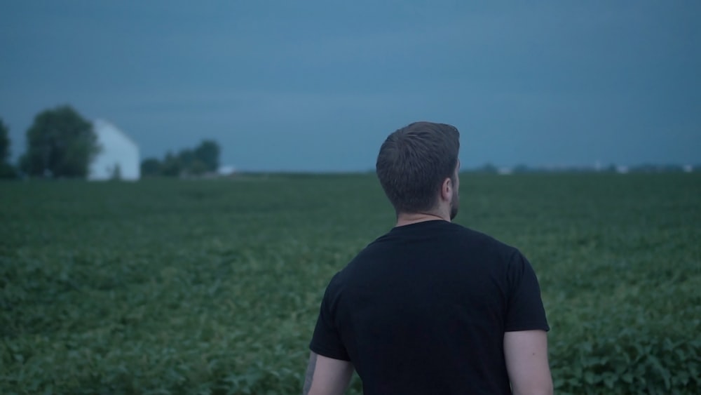 man in black t-shirt standing on green grass field during daytime