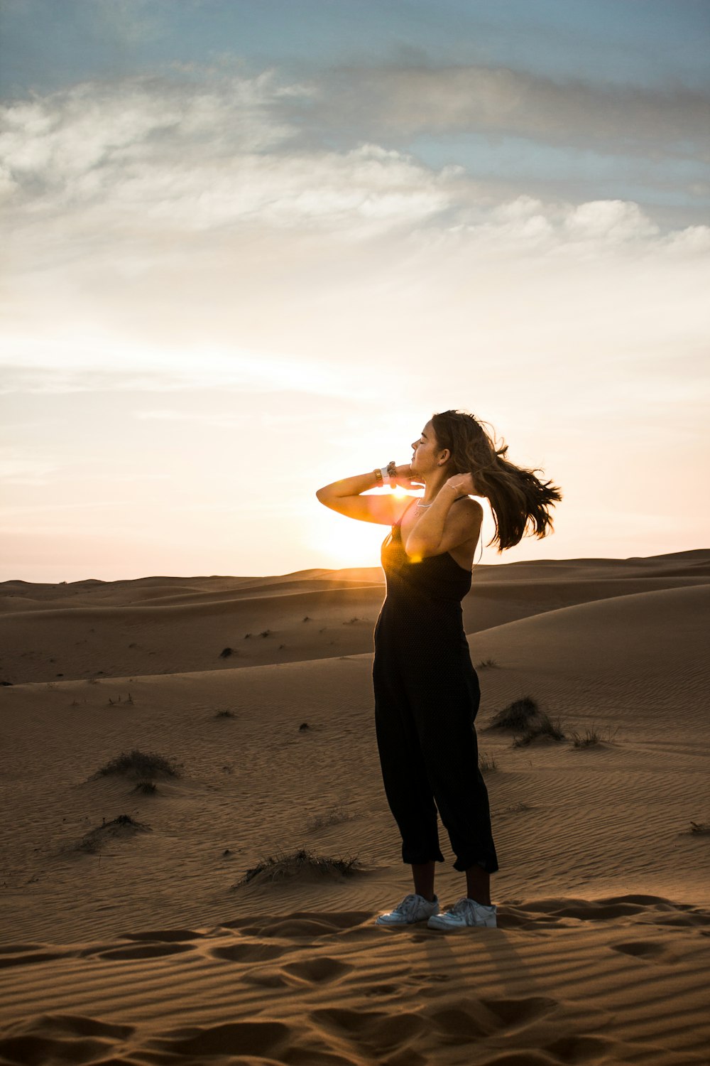 woman comb her hair standing on sand during daytime