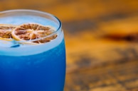 Close-up of a cocktail glass with vibrant colors on a wooden bar.