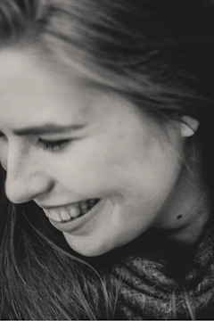 A close-up portrait of a woman laughing naturally in soft natural light.