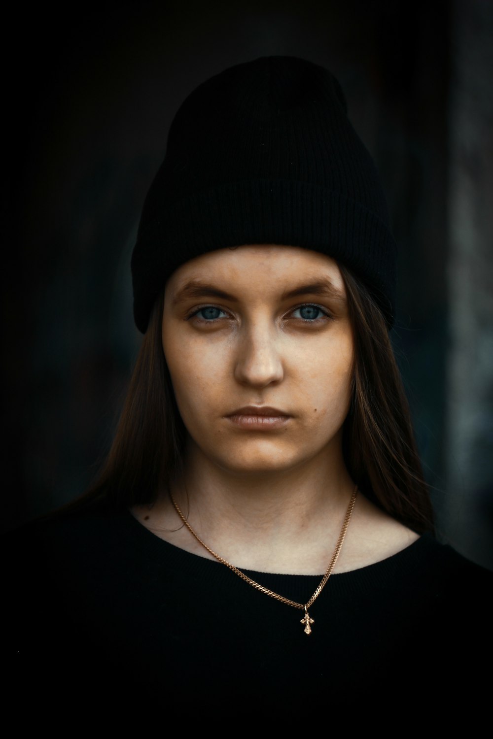 woman in black shirt wearing black beanie and gold-colored necklace with pendant