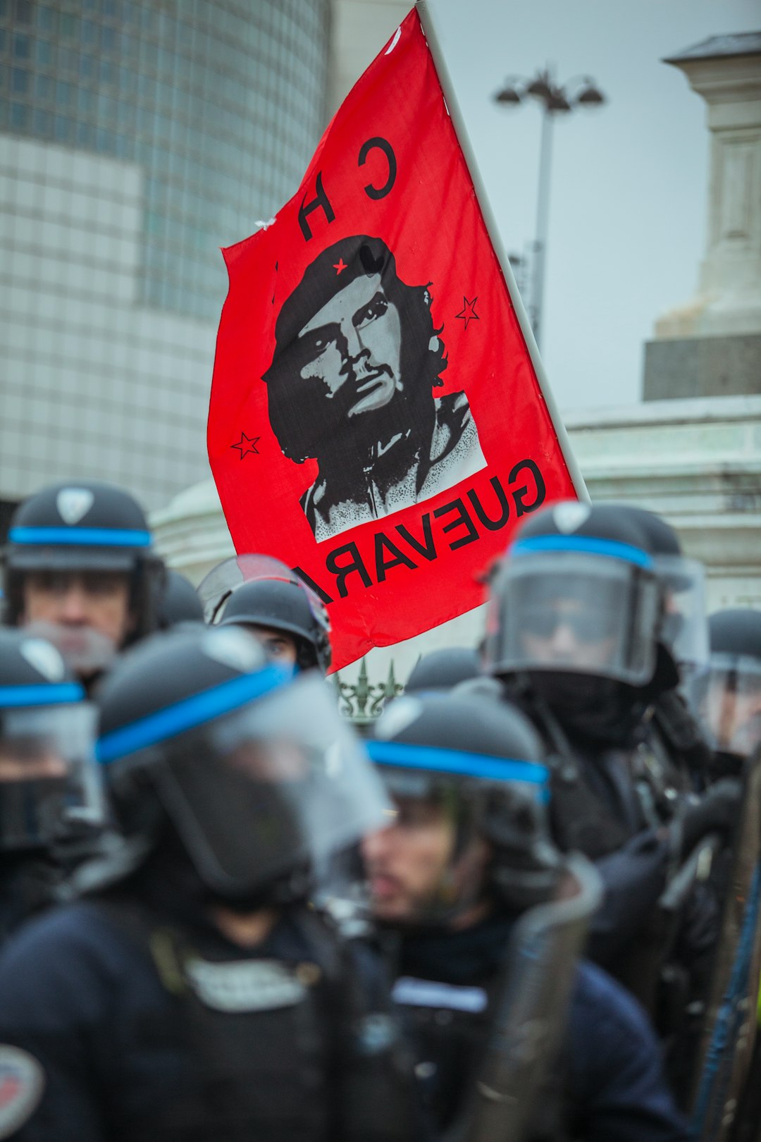 red Che Guevara flag near group of police during daytime