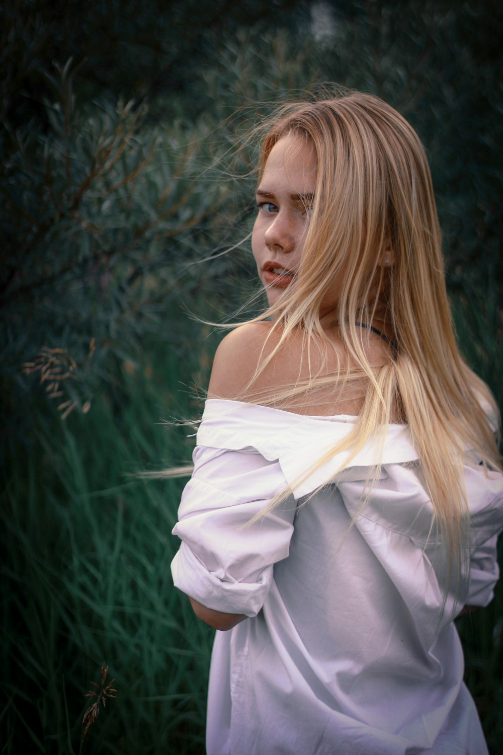 woman in white top standing beside plants