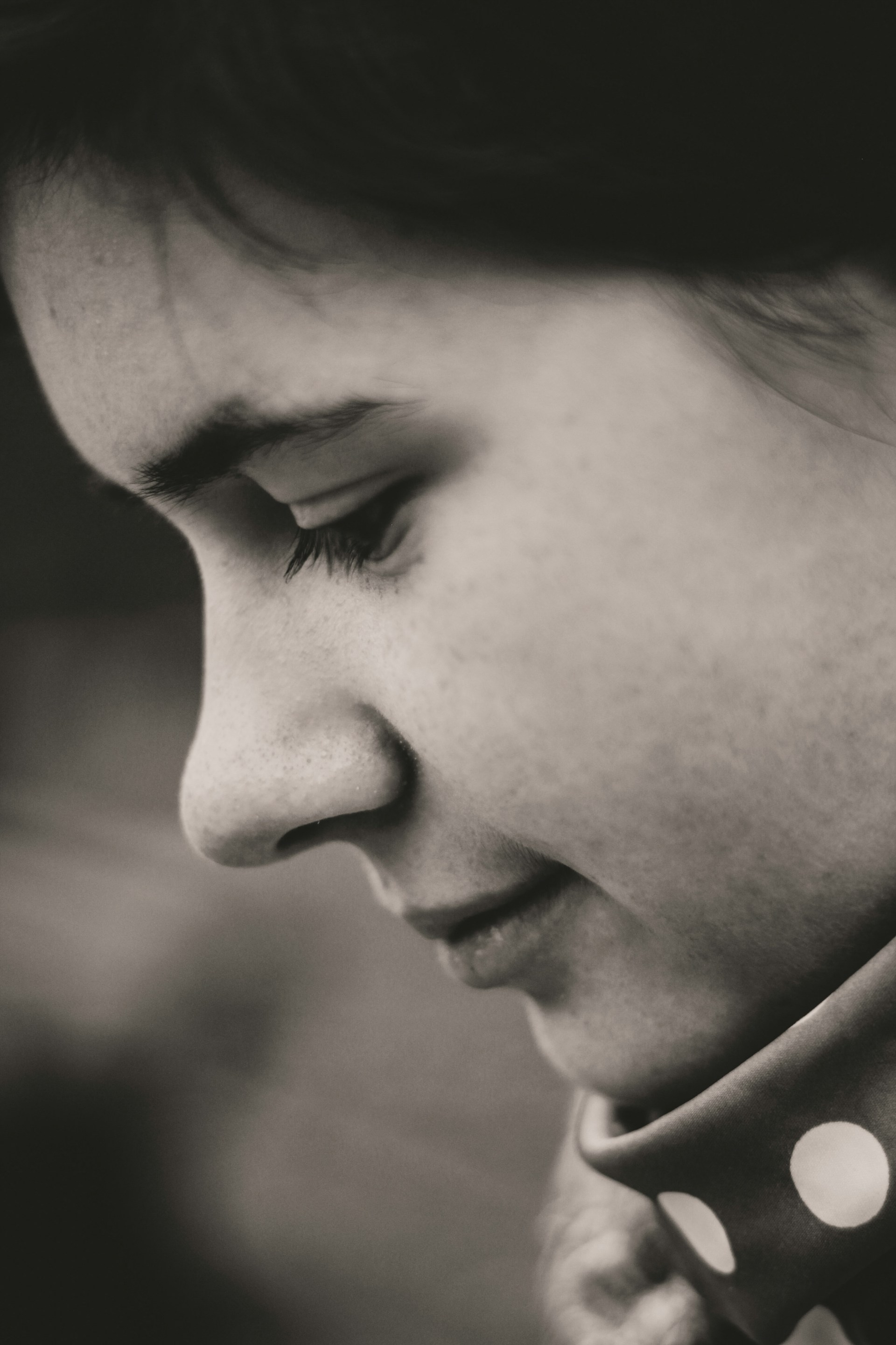 An intimate close-up of a subject's face framed by city shadows, capturing a moment of quiet reflection.