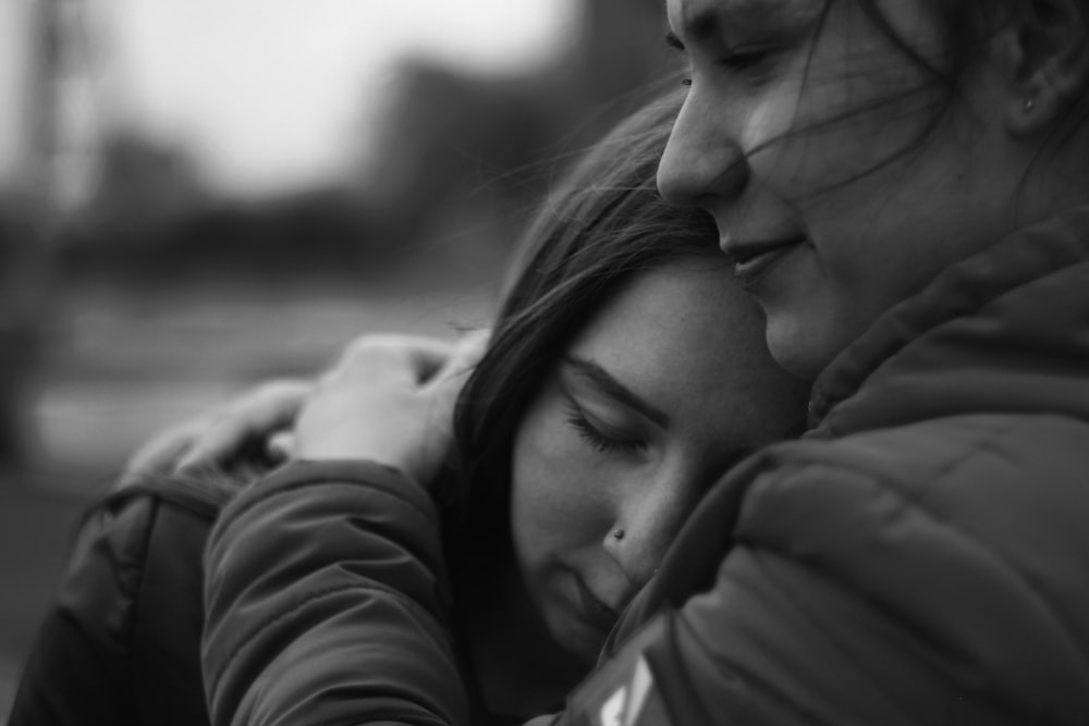 grayscale photography of woman hugging another woman