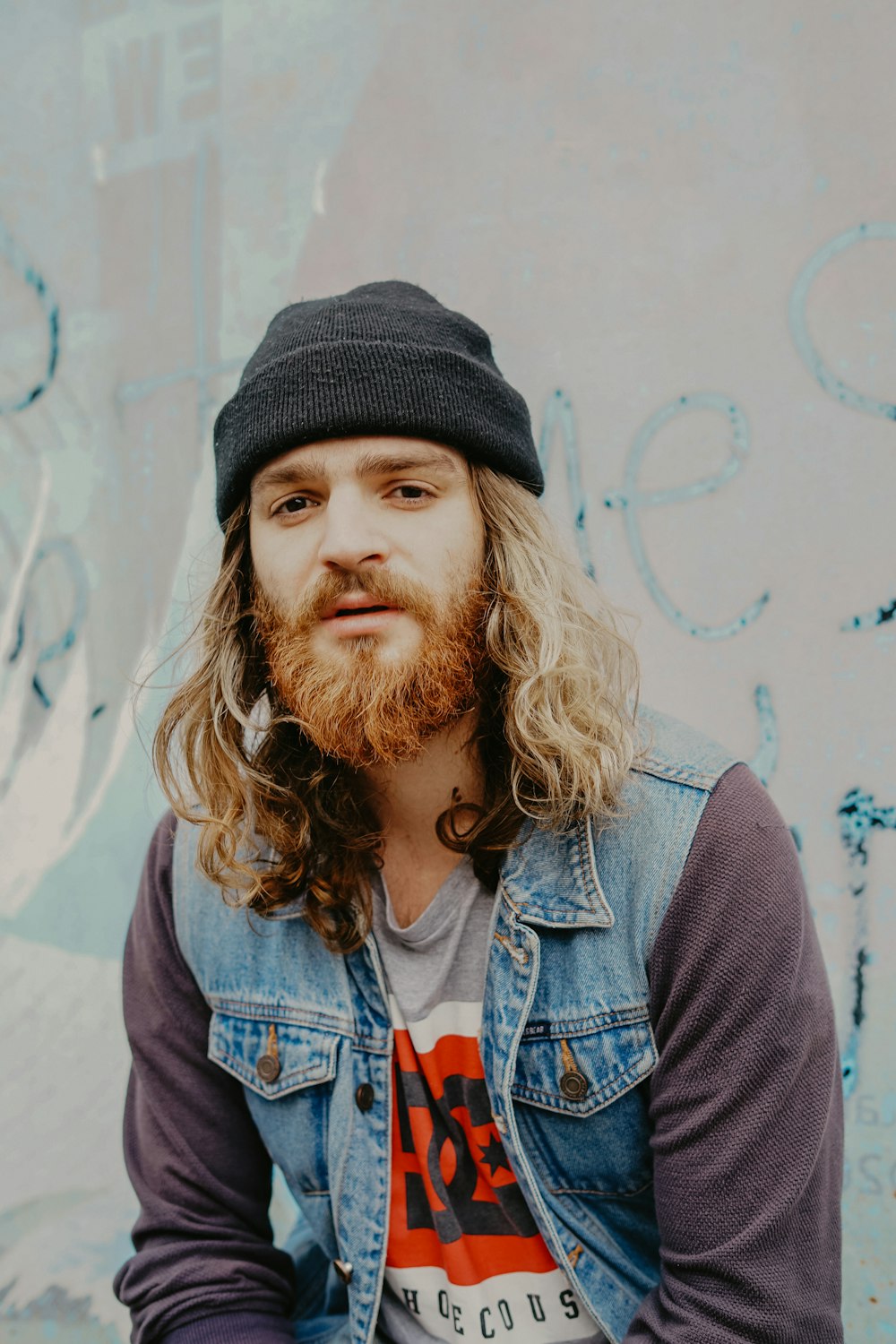 man wearing black knit cap sitting in front of white wall