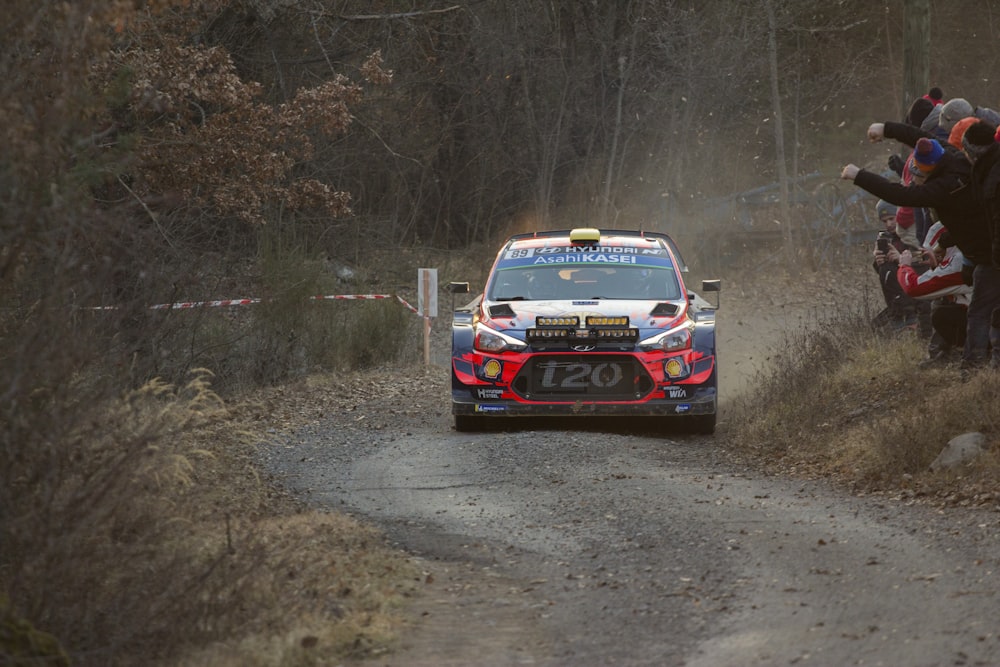 stock car passing on road beside people cheering