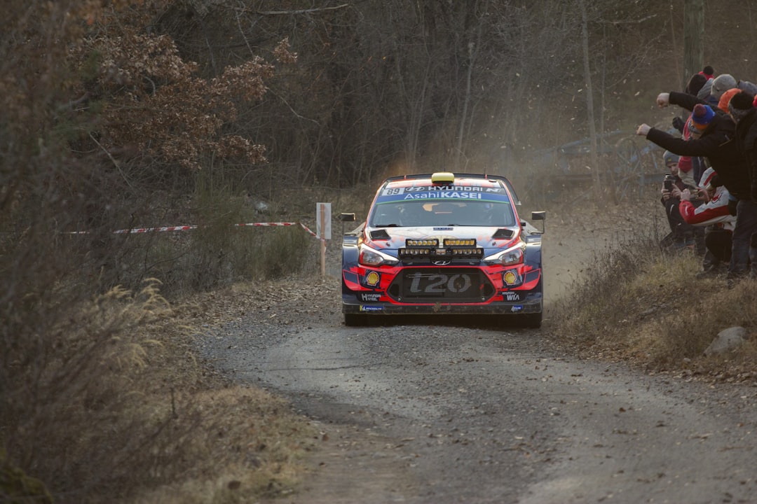 stock car passing on road beside people cheering,
