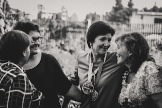 A vibrant group of young women laughing and chatting outdoors in Fontainebleau, with soft violet hues in the background.