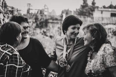A group of women smiling and sharing stories during a community gathering outdoors.