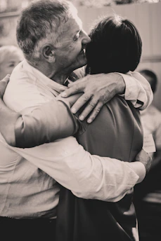 Smiling individuals warmly embracing each other in a cozy community center.