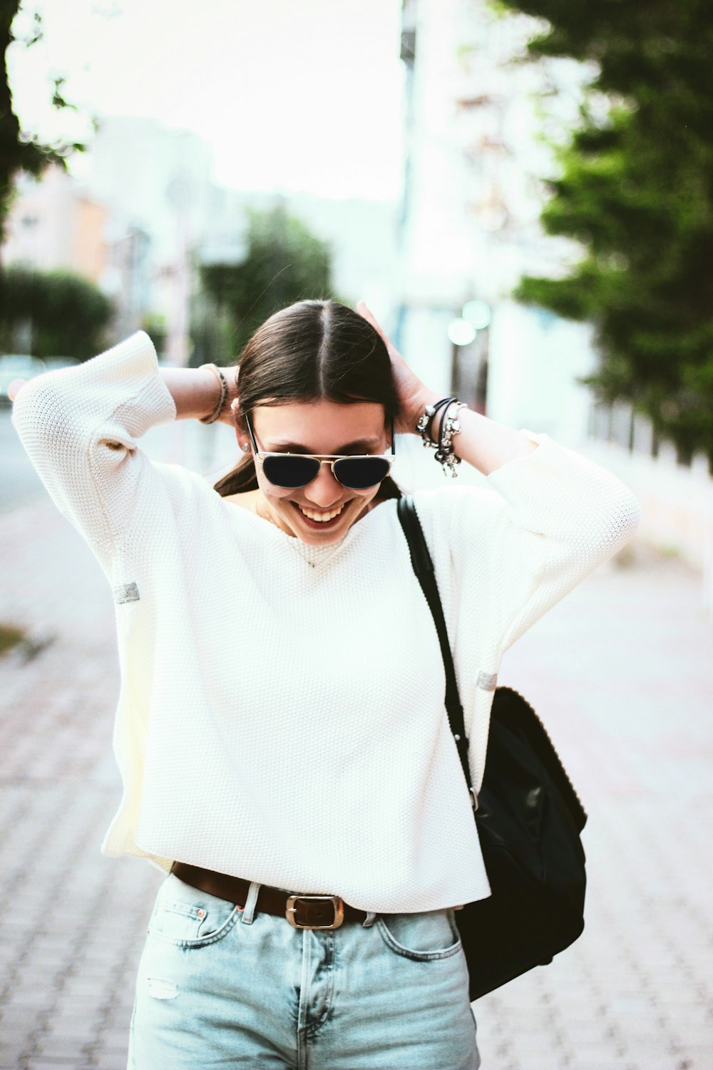 smiling woman in white knitted sweater carrying black backpack