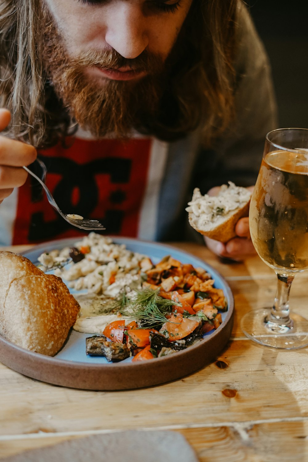 man eating bread and plate near filled wine glass