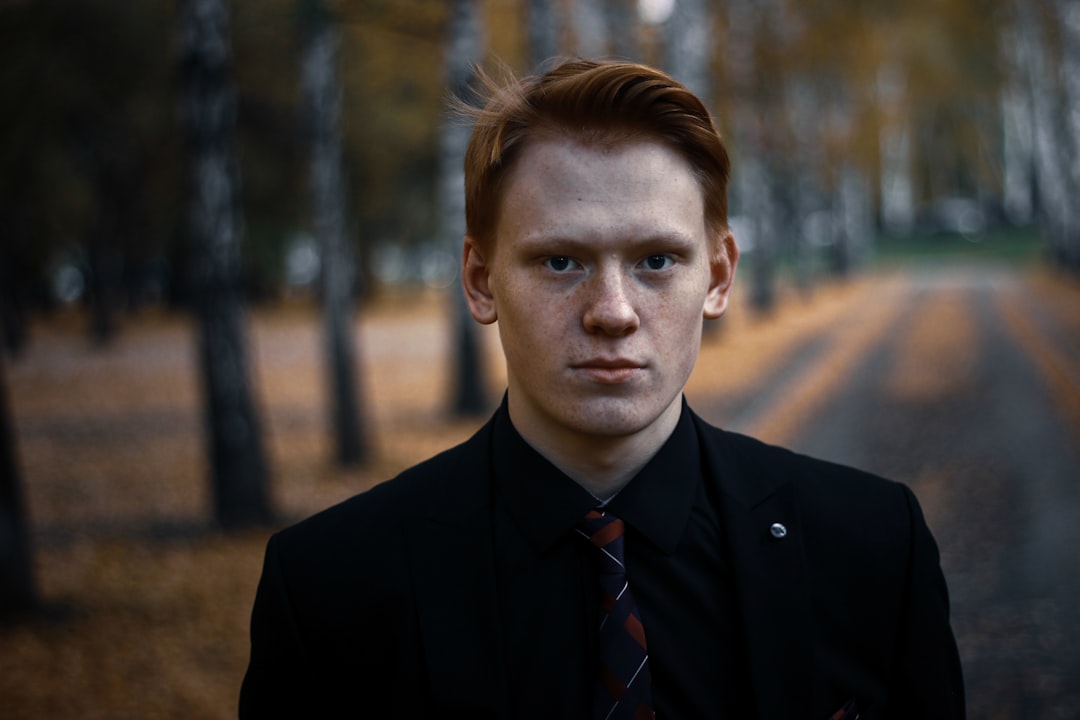 man in black suit jacket beside trees