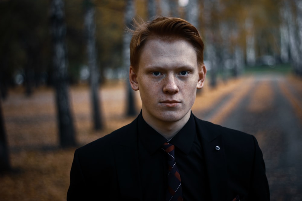 man in black suit jacket beside trees