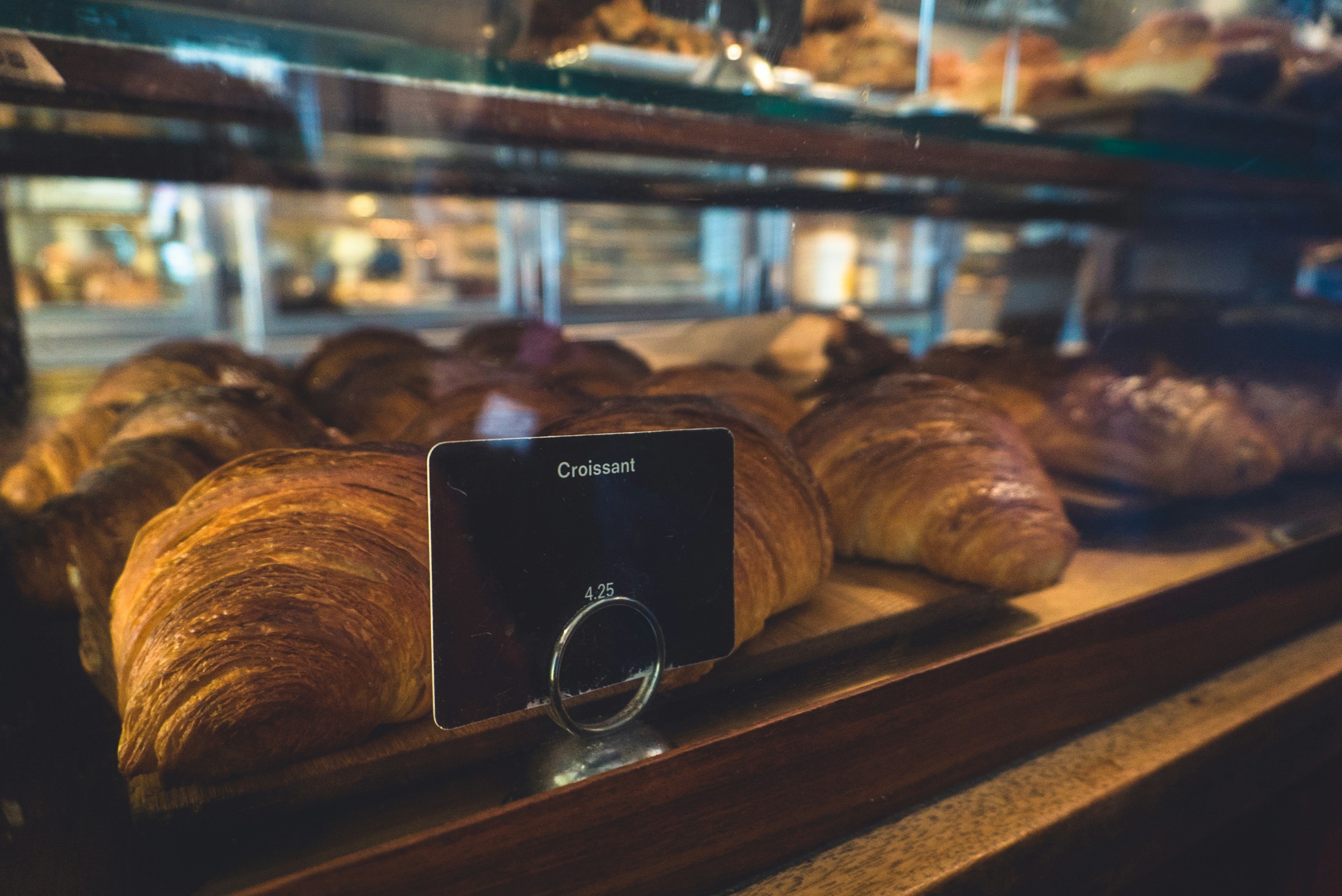 Rows of fresh baked croissant behind counter