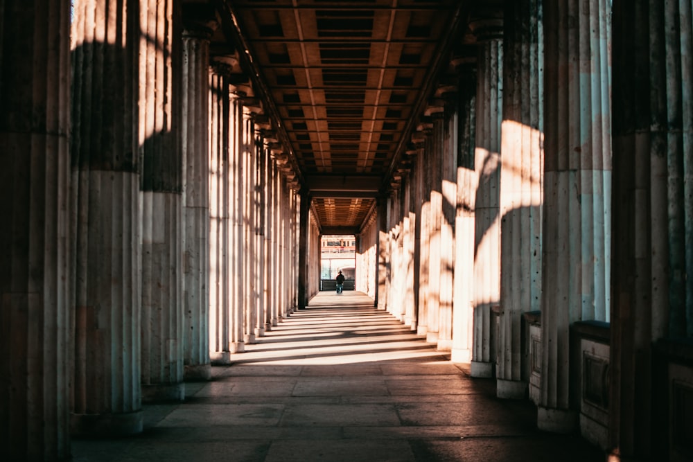 brown concrete hallway surrounded by pillars