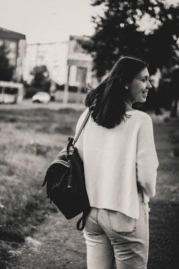 Young woman smiling outdoors carrying a colorful casual handbag in an urban setting