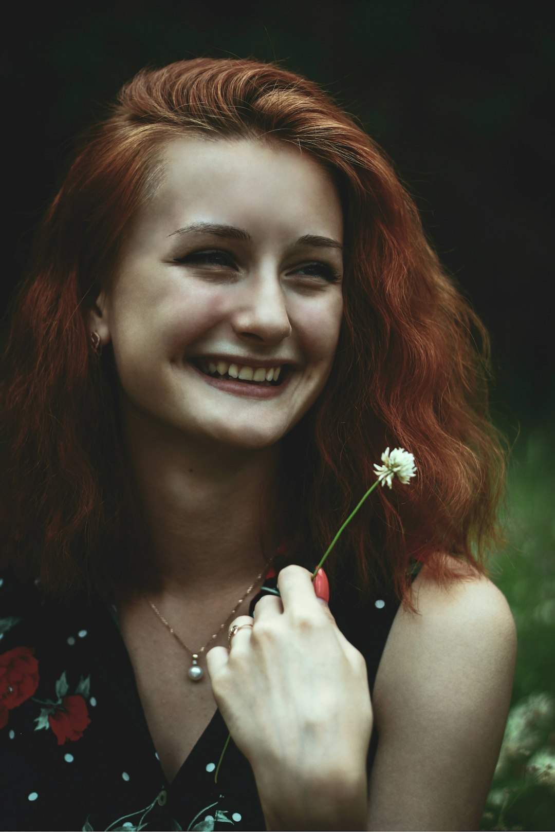 woman smiling while holding white flower