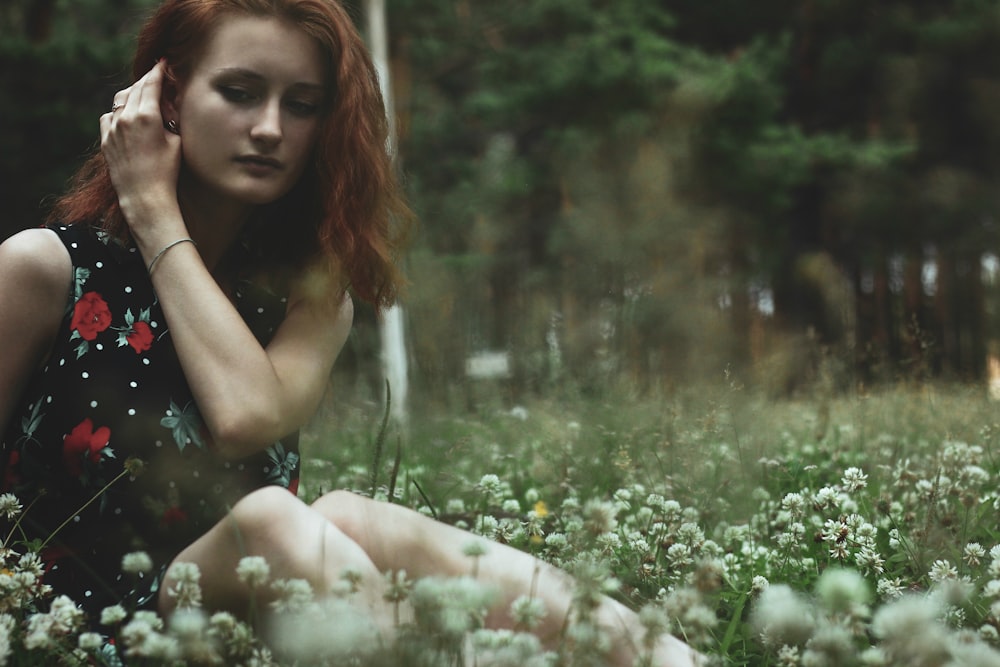 woman sitting on bed of white-petaled flowers