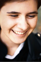 A close-up of a celebrity smiling warmly during a media event.