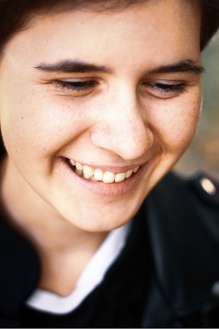 A close-up of a relaxed person smiling under a blue LED light during a teeth whitening session.