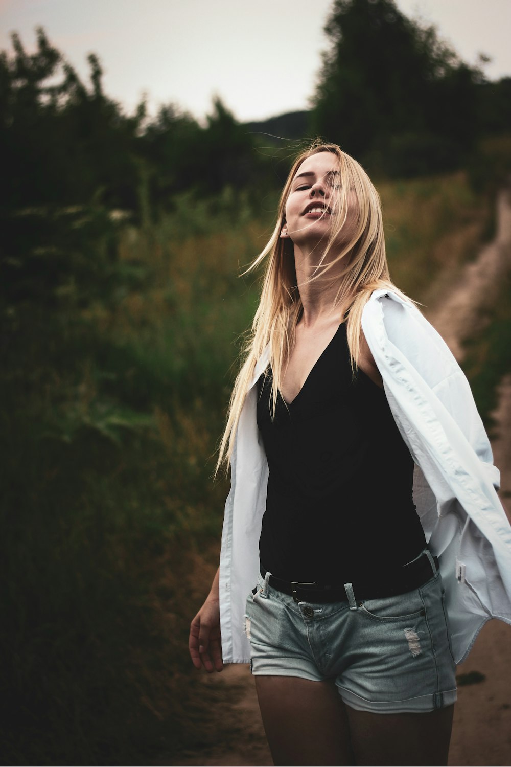 woman looking up while standing near green grass field