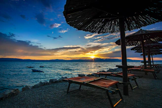Sunset over the calm sea with beach loungers and soft golden light