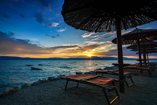 Sunset over the calm sea with beach loungers and soft golden light