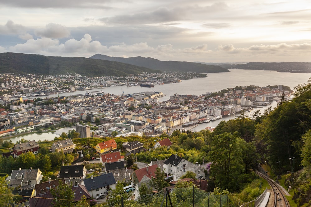 buildings in town facing body of water and mountains under cloudy sky