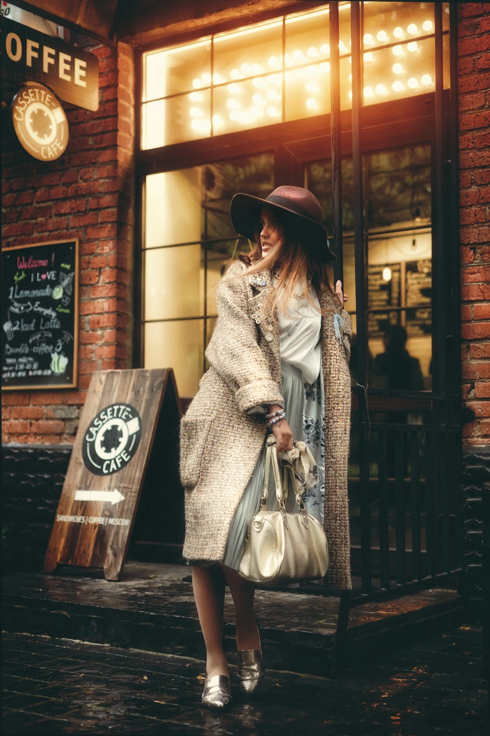 woman standing while holding leather bag beside coffee store