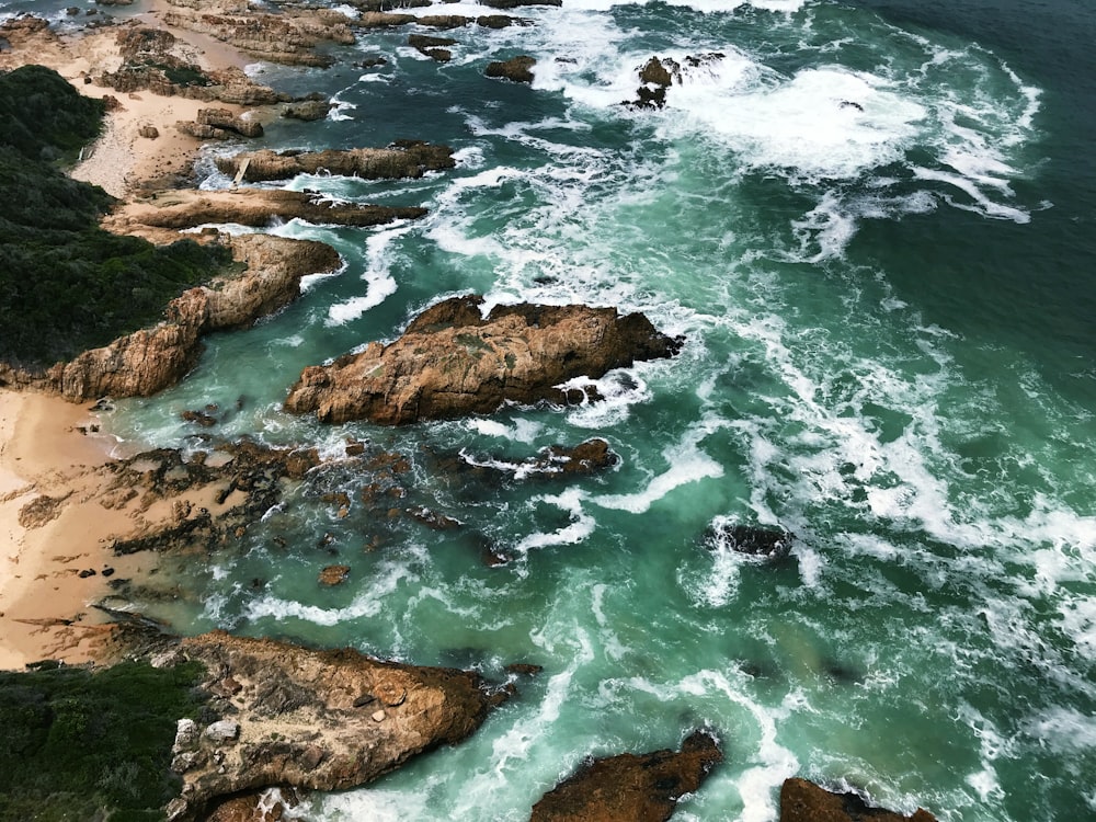 seawaves crashing to stones formation during daytime