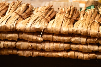 Bundles of dried leaves are tightly tied together with string, stacked in a neat, organized manner. The leaves have a brownish, natural hue and appear to be used for traditional or organic purposes.