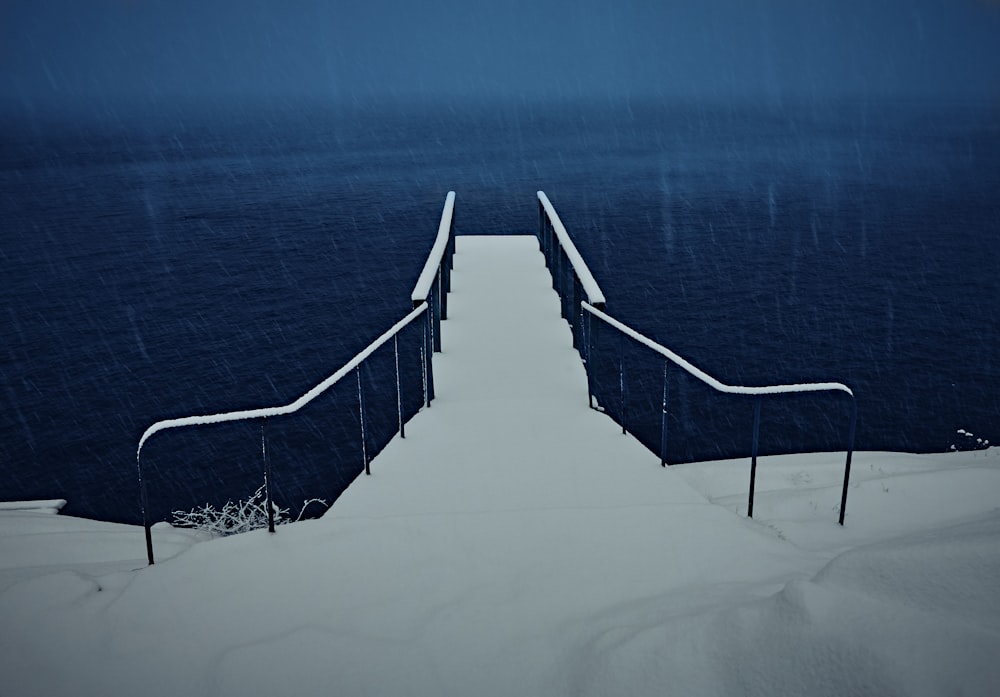 Escaleras cubiertas de nieve y muelle cerca del cuerpo de agua