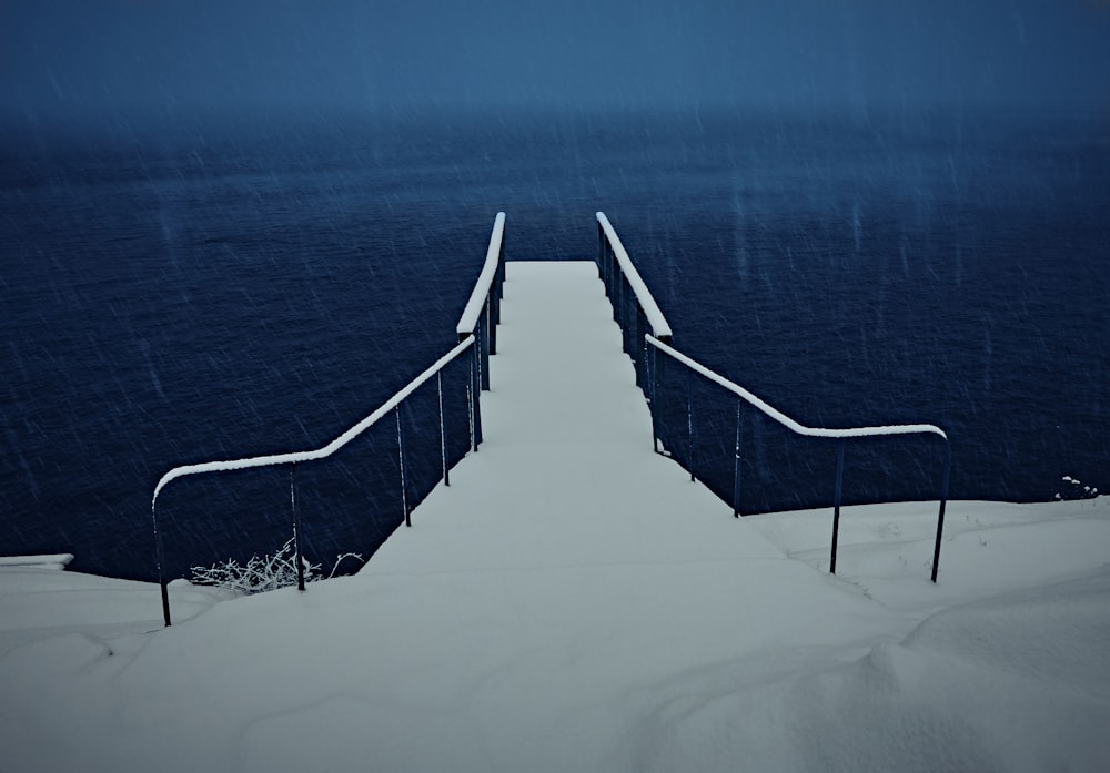 snow covered stairs and dock near body of water