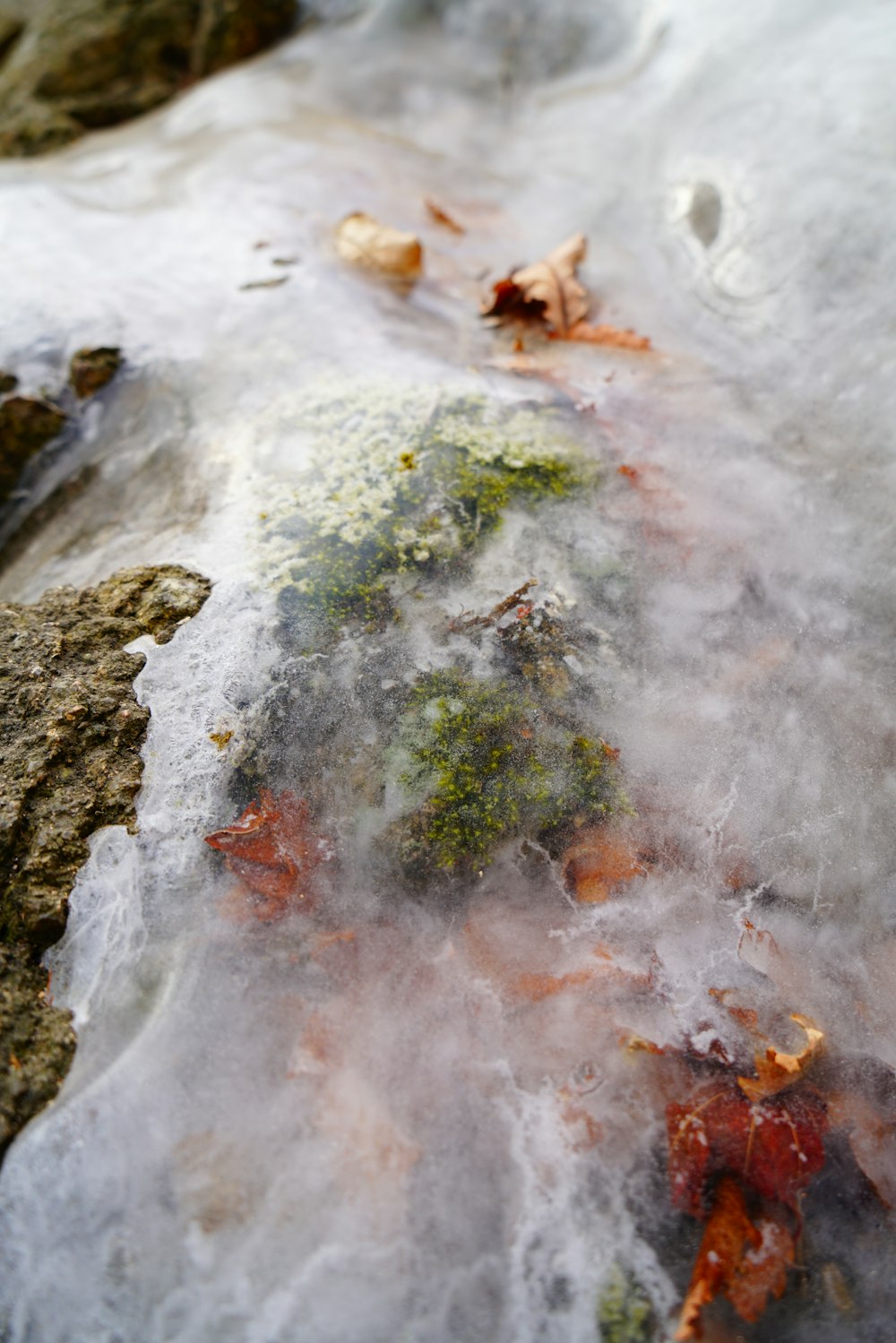 a rock covered in ice and water next to a body of water