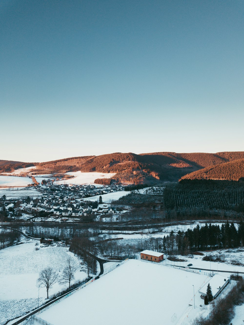 Rotes Haus, umgeben von schneebedecktem Feld und in der Nähe des Flusses