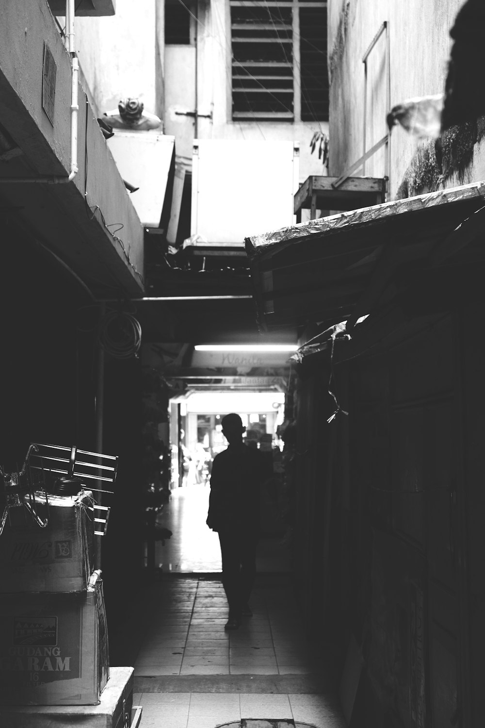 grayscale photo of man standing on pathway between houses