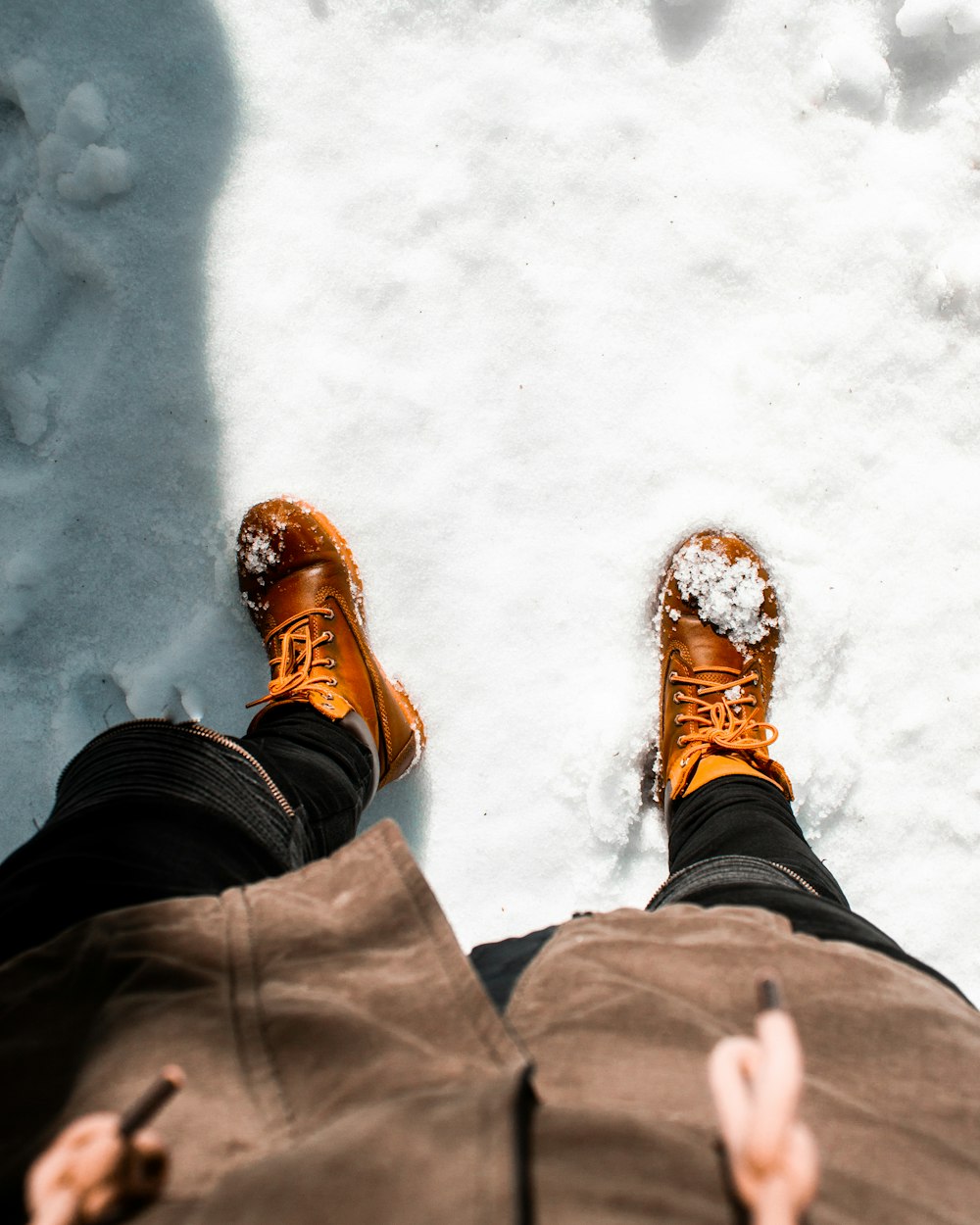 雪の上に立つ茶色の革の作業靴を履いた人