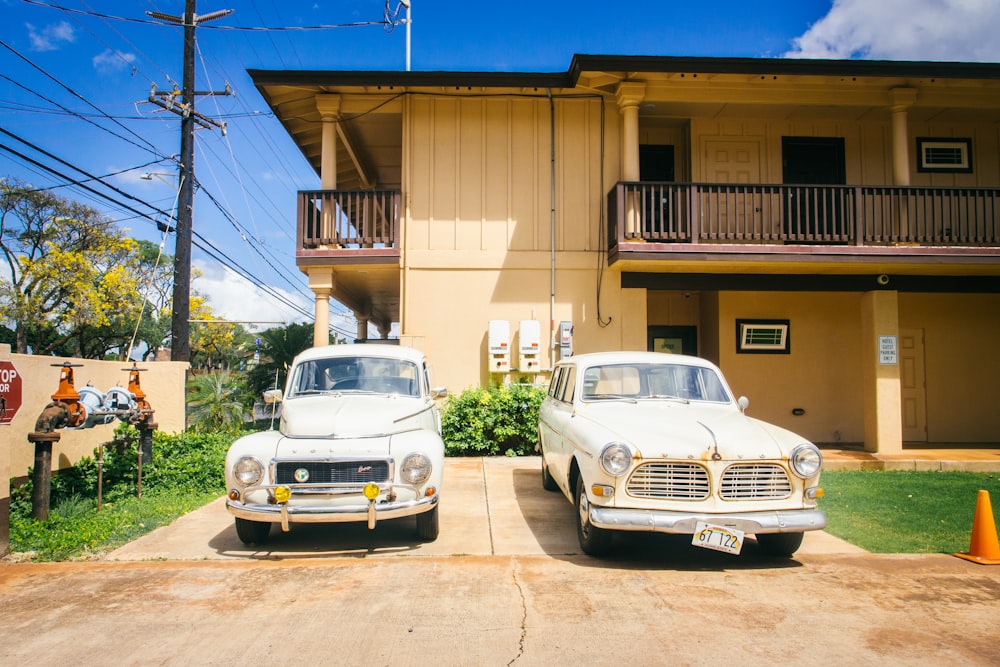 two white vehicle park beside brown house